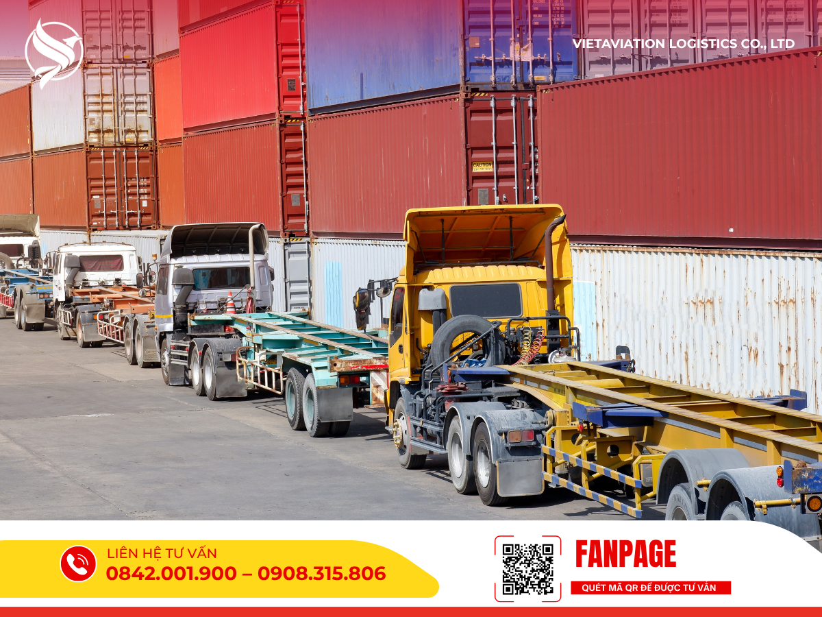 Hàng loạt xe đầu kéo và rơ-moóc vận chuyển container đỗ dọc theo nhau trong khu vực cảng biển hoặc bãi tập kết hàng.