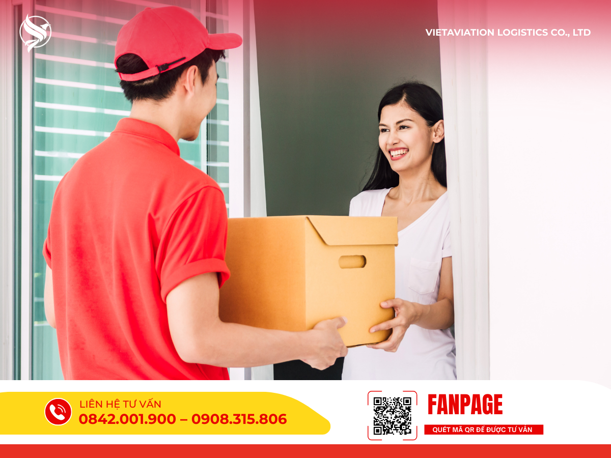 Hình ảnh nhân viên giao nhận trong đồng phục đỏ đang trao kiện hàng các tông tận tay cho khách hàng nữ ngay tại cửa nhà.