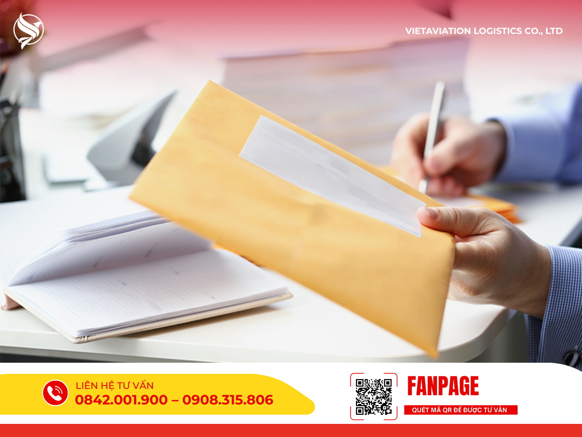 Hình ảnh một người đang cầm phong bì màu vàng và dùng bút ghi chép trên bàn làm việc.