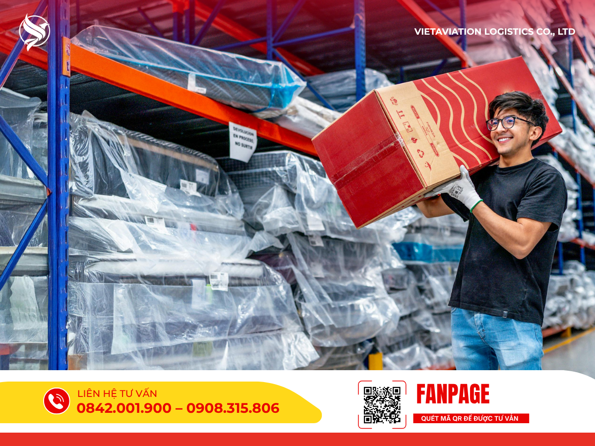 Hình ảnh một nam nhân viên trẻ đeo kính và mang găng tay bảo hộ đang mỉm cười vác một thùng carton màu đỏ lớn trên vai, phía sau là hệ thống kệ sắt chứa nhiều hàng hóa được bọc nilon cẩn thận trong kho.