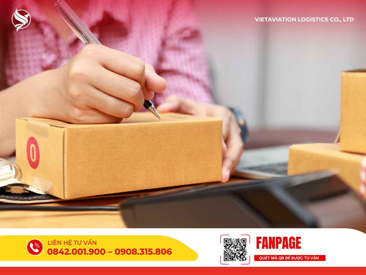 Hình ảnh tay cầm bút viết thông tin lên thùng hàng carton nhỏ.