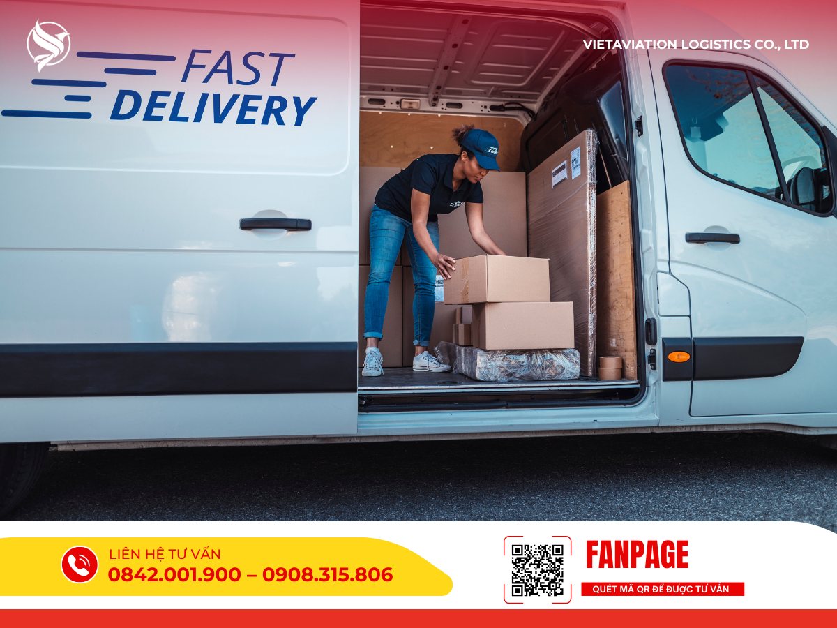 Hình ảnh một nhân viên nữ đội mũ lưỡi trai đang sắp xếp các thùng carton bên trong khoang của một chiếc xe tải giao hàng màu trắng có in dòng chữ Fast Delivery bên hông.